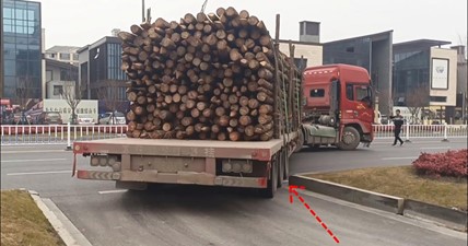 The truck driver backs up on the city road. Superb driving skills.